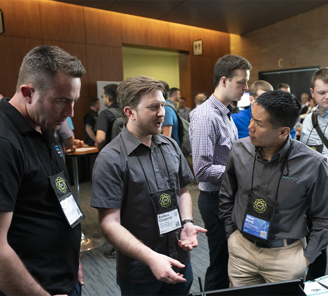 Three employees are interacting with each other at an ICC conference booth